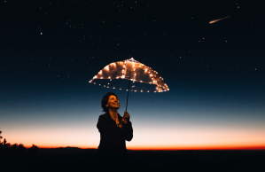 Woman holds illuminated umbrella under starry sky