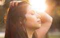 Woman running her hand through her hair closing her eyes face to the sun.