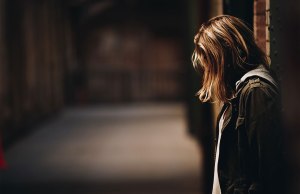 woman leaning against wall looking down