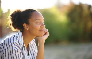 Happy woman sitting in nature while enjoying the weather