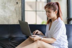 Woman with pink hair looking at a laptop