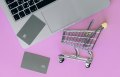 silver shopping cart with silver credit cards and silver macbook computer