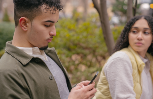 woman looking jealously at man while on his phone