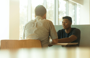 two men sitting at table talking