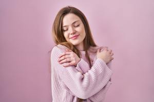 Woman in pink hugging herself