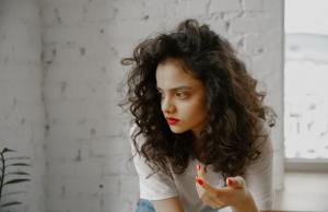 Thoughtful woman with red lipstick and red fingernails