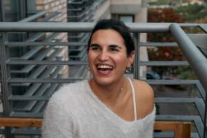 Woman in gray sweater laughing on a balcony