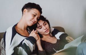 Young attractive female couple read together and snuggle in bed