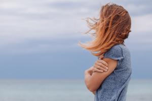 Woman with hair in her face looking at the sea