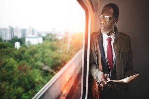 Man reading on a train by a window