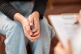 Young woman's hands clasped as she sits across from psychiatrist during a session