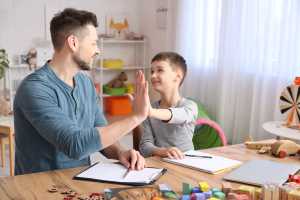 Behavioral therapist sitting with autistic child in play therapy room