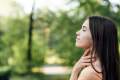 Woman holding her neck outside in the woods