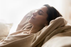 White woman relaxing on a bed with soft white light in the background