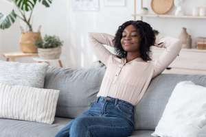 Woman leaned back on a couch with arms behind her head