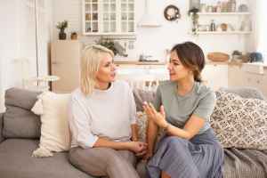 Mother and daughter talk on a gray couch