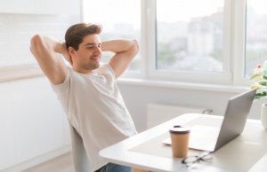 Happy smiling man having a rest after solving all the tasks at home