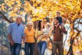 Family of multiple generations walking under yellow leaves in fall