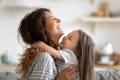 Mother in a gray shirt hugging her young daughter