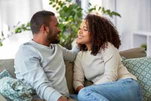Man and woman sitting on a gray couch talking