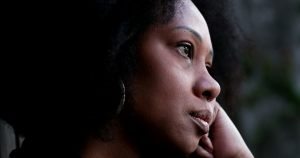 Woman with dark skin staring out a window