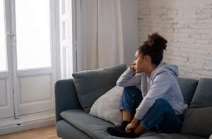 Woman in gray sweatshirt on a gray couch