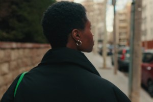 Woman walking alone on a city street, seen from behind, looking ahead