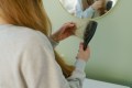 Woman with red hair pulling hair out of a bruch