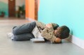 Child with DMDD throwing a tantrum on the floor of a school hallway