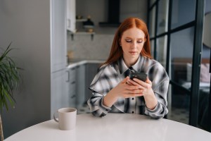 Woman sitting at a table texting someone with a serious look on her face